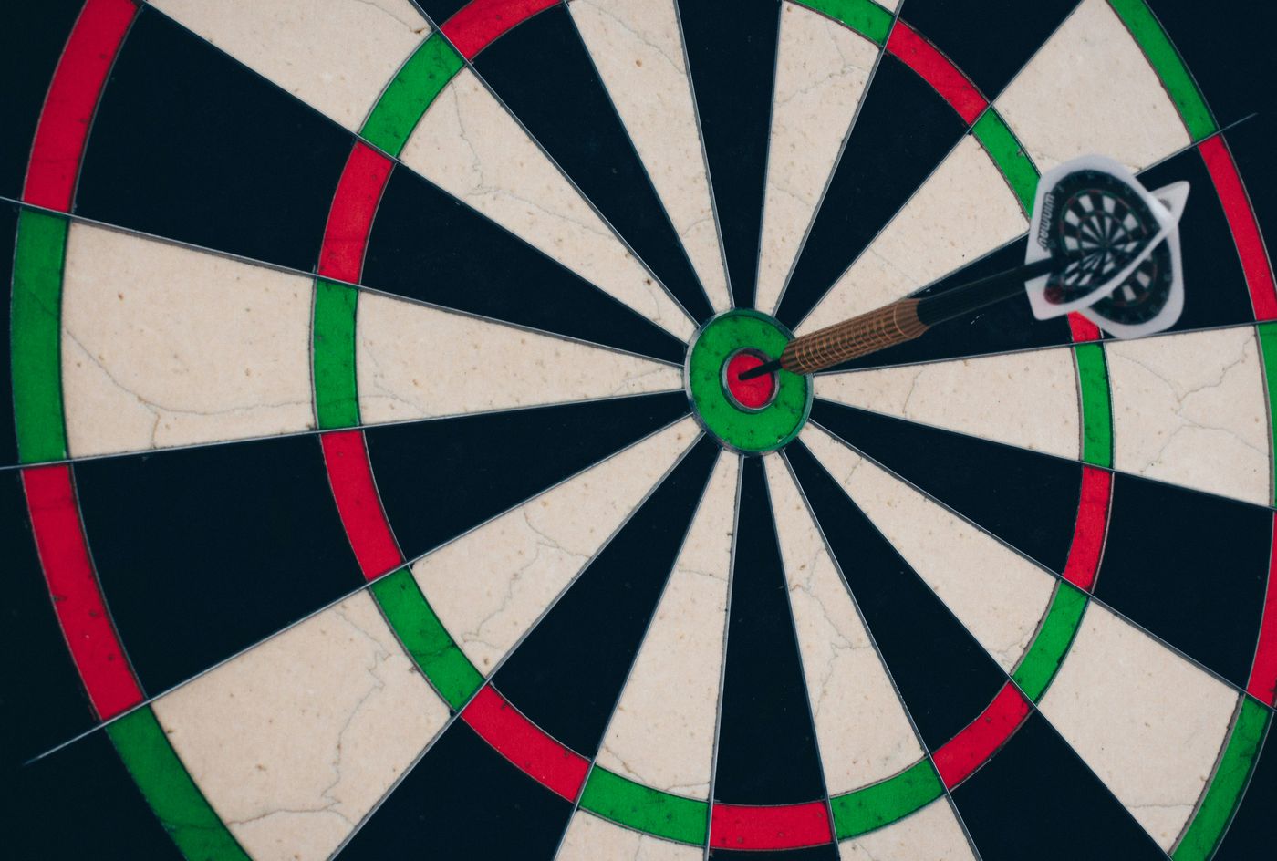 A dart in the bullseye of a well-used dartboard